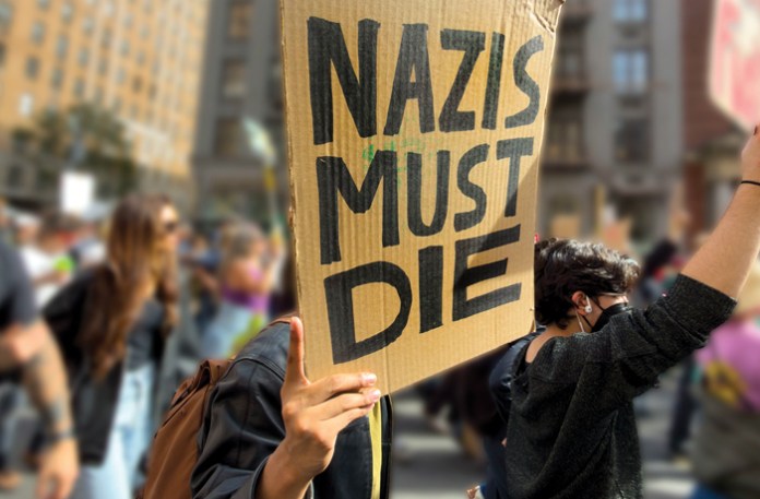 Protester holds a sign that says "Nazis must die" at a "No Kings" rally.