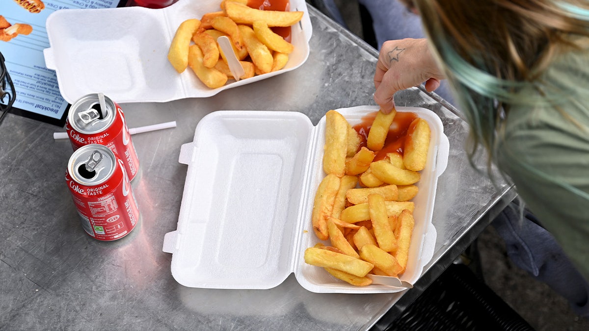 People eating french fries from a takeaway box 