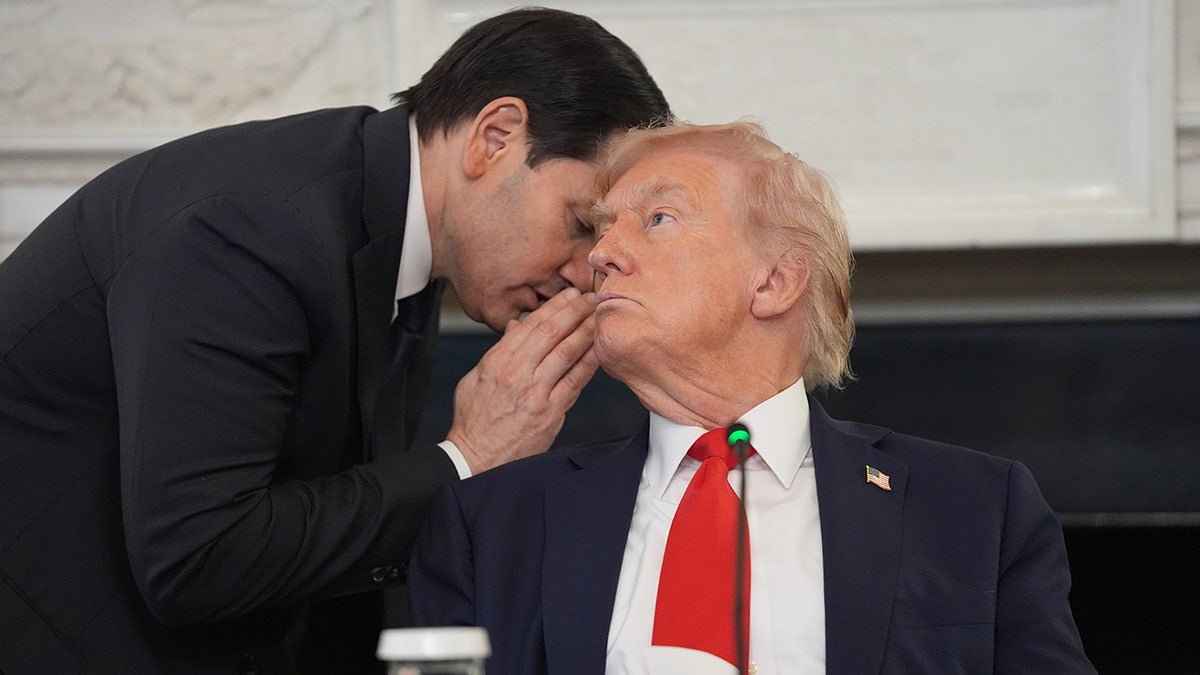 Secretary of State Marco Rubio whispers to President Donald Trump, who is holding the note Rubio handed to him, during a roundtable meeting on antifa in the State Dining Room at the White House, Wednesday, Oct. 8, 2025, in Washington. (AP Photo/Evan Vucci)