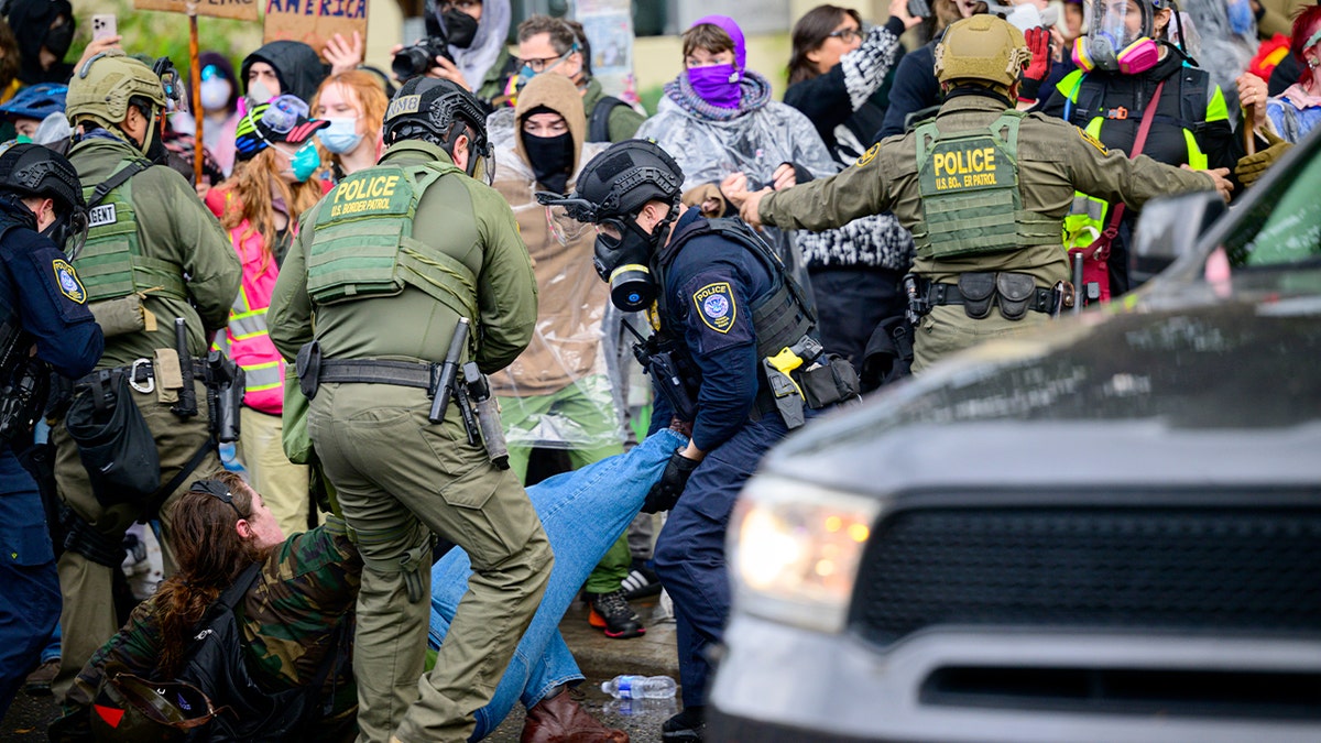 Officers restrain a demonstrator during an arrest outside a federal immigration facility amid a protest.