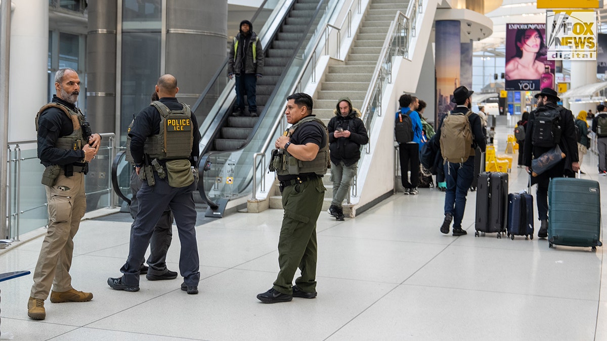 ICE agents walking through a terminal at JFK Airport.