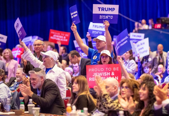 Attendees react after a live satellite video speech by Republican 