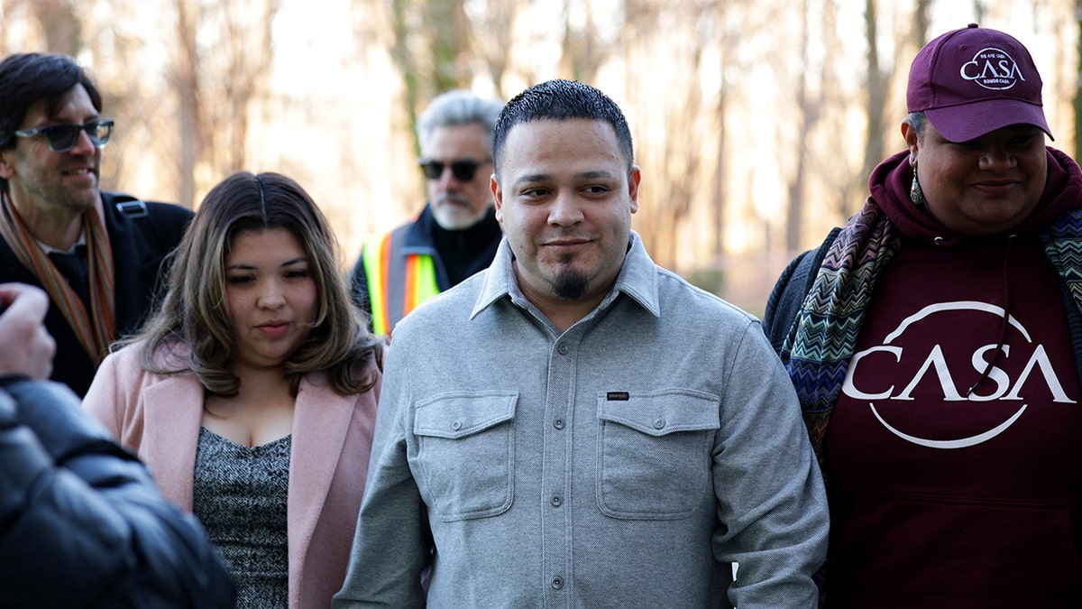 Kilmar Abrego Garcia walking with Jennifer Vasquez Sura and Simon Sandoval-Moshenberg outside a U.S. District Court building.