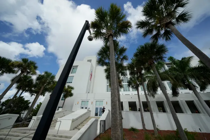 A police officer stands beside an entrance to the Alto Lee Adams Sr. U.S. Courthouse, Aug. 15, 2023, in Fort Pierce, Florida. The federal judge overseeing the classified documents prosecution of Trump is expected to set a trial date during a court hearing on March 1, 2024.