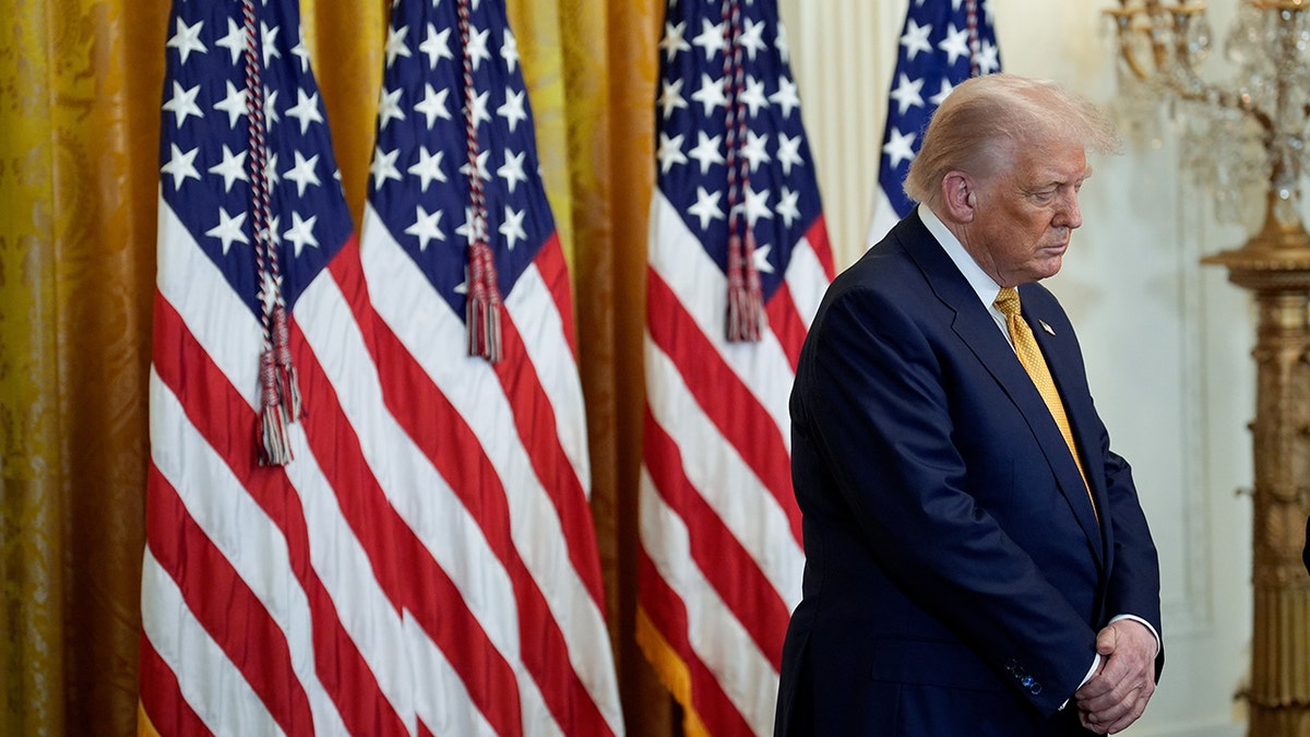 President Donald Trump bows his head in prayer in the East Room of the White House