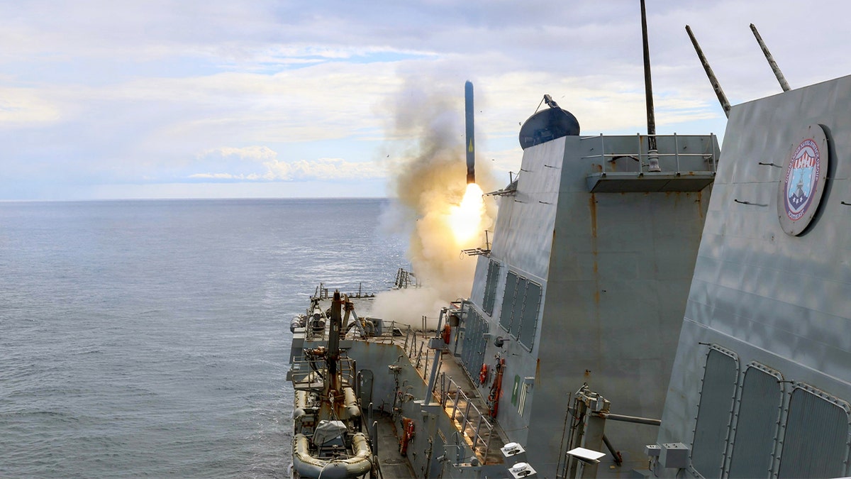 A U.S. Navy destroyer launches a missile from its deck while underway at sea.