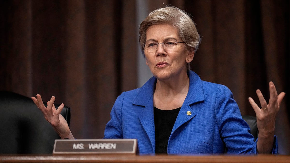 Sen. Elizabeth Warren speaking to a staff member before a Senate Banking Committee hearing