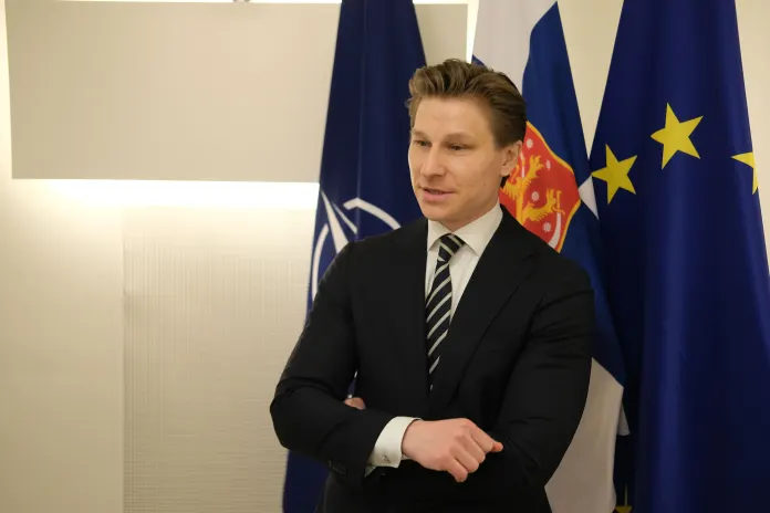 Antti Häkkänen stands in front of Finnish, European Union, and NATO flags