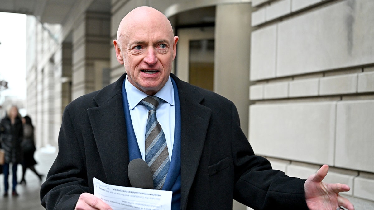Mark Kelly addresses reporters while standing outdoors near a courthouse.