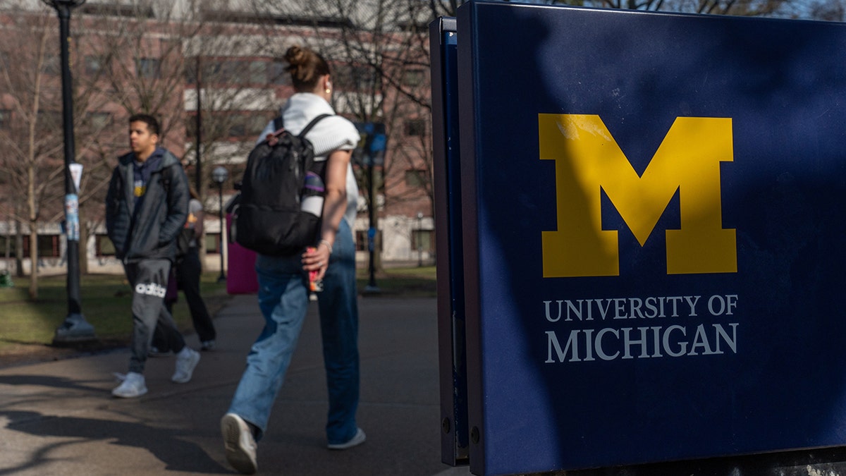 University of Michigan sign as student walks past