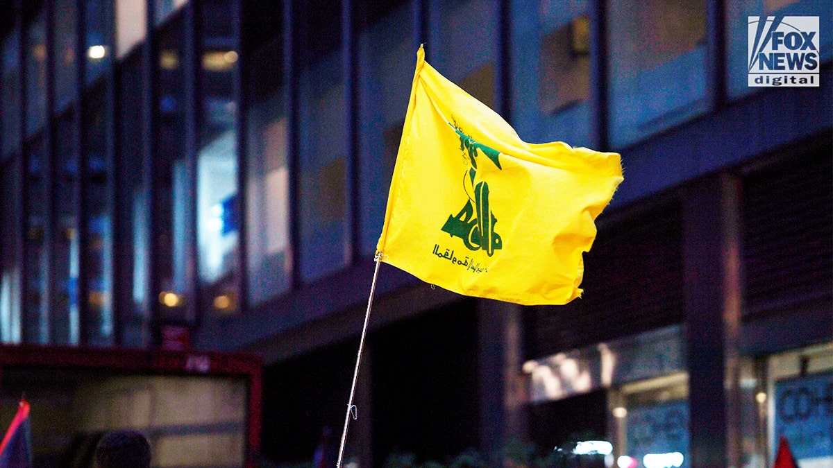 Yellow Hezbollah flag waving during an anti-Israel protest in Manhattan at night.