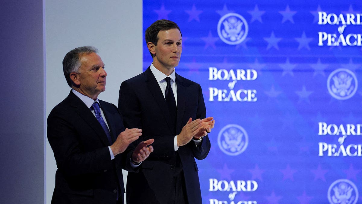 Jared Kushner and Steve Witkoff standing at a podium during a charter announcement in Davos