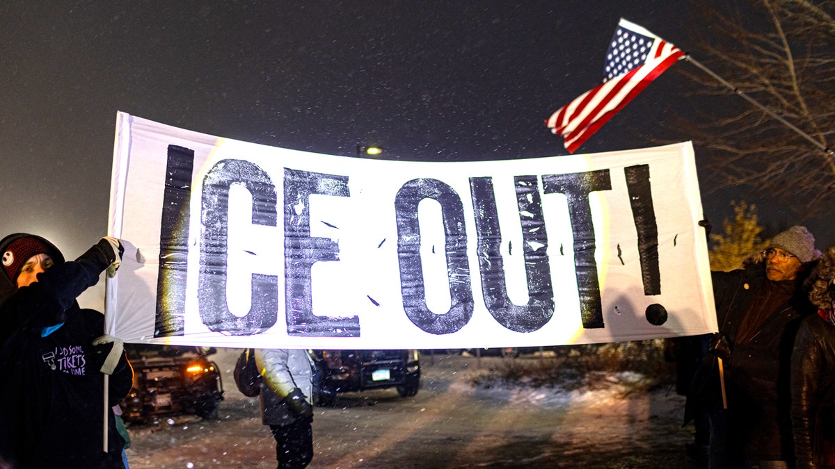 Protesters holding a large anti-ICE sign outside the Henry Bishop Whipple Federal building in Minneapolis