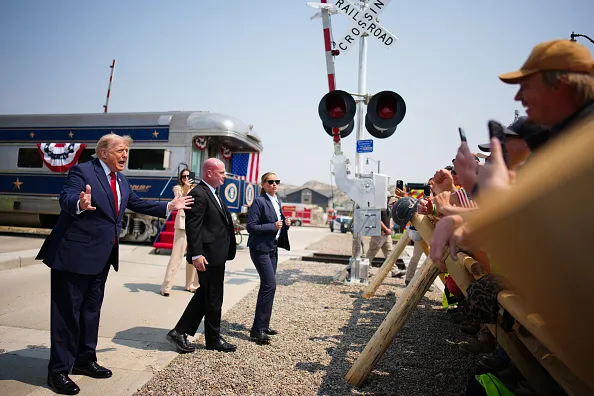 President Donald Trump greets onlookers after arriving in a Freedom250-themed train ahead of a dedication ceremony for the Theodore Roosevelt Presidential Library.