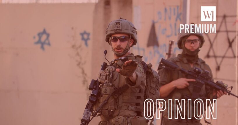 An armed Israeli soldier gestures while standing next to another soldier in the Old City of Hebron, the occupied West Bank, on June 27, 2026.