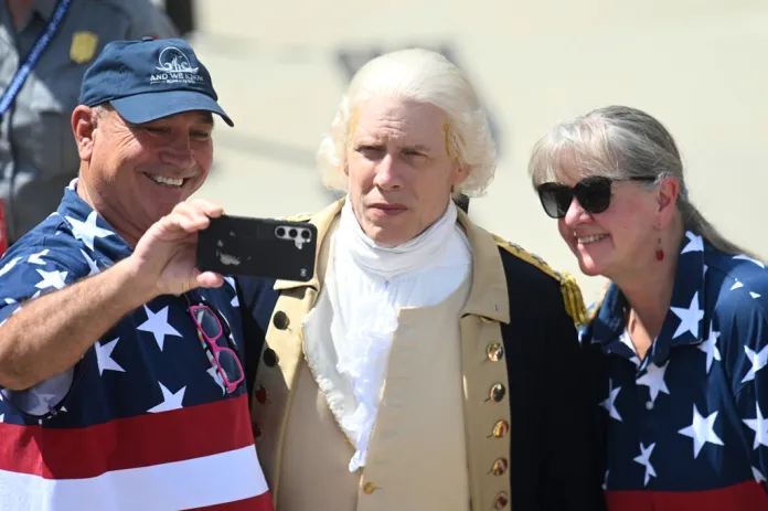 Attendees take a photo with a man dressed in a George Washington costume at Mount Rushmore National Memorial, Friday, July 3, 2026, in Keystone, S.D.