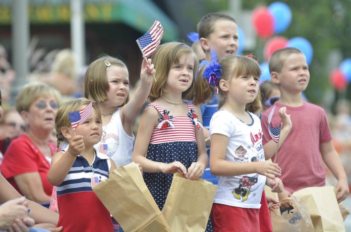 Children wave the Red, White and Blue during the 4th of July Parade through downtown Clarkston, Mich., Monday, July 4, 2011. (AP Photo/The Oakland Press, Doug Bauman)