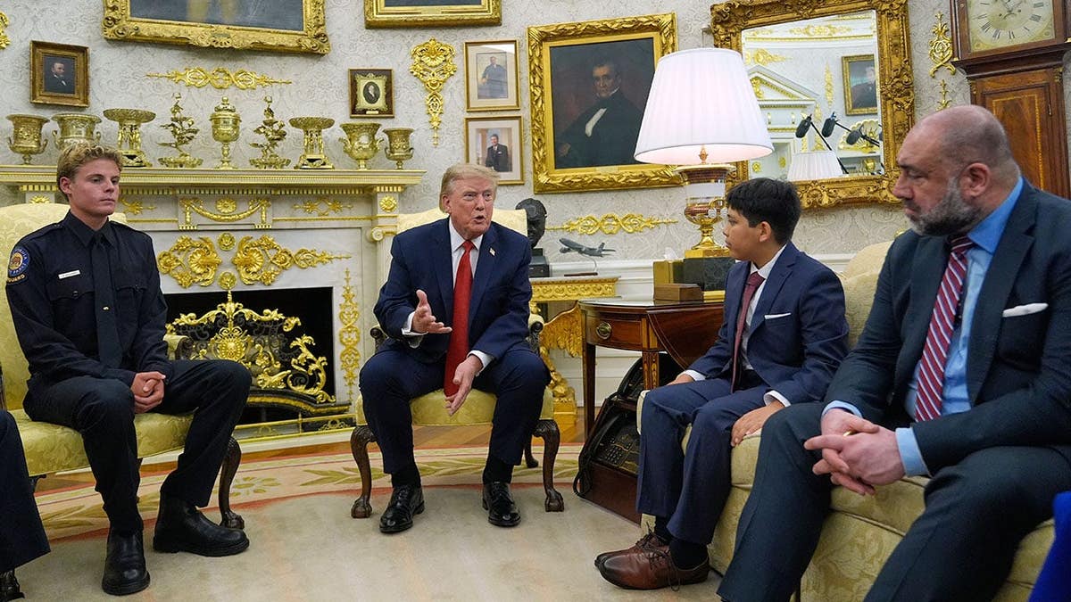 Ryder Williams stands with President Donald Trump in the Oval Office as they speak.