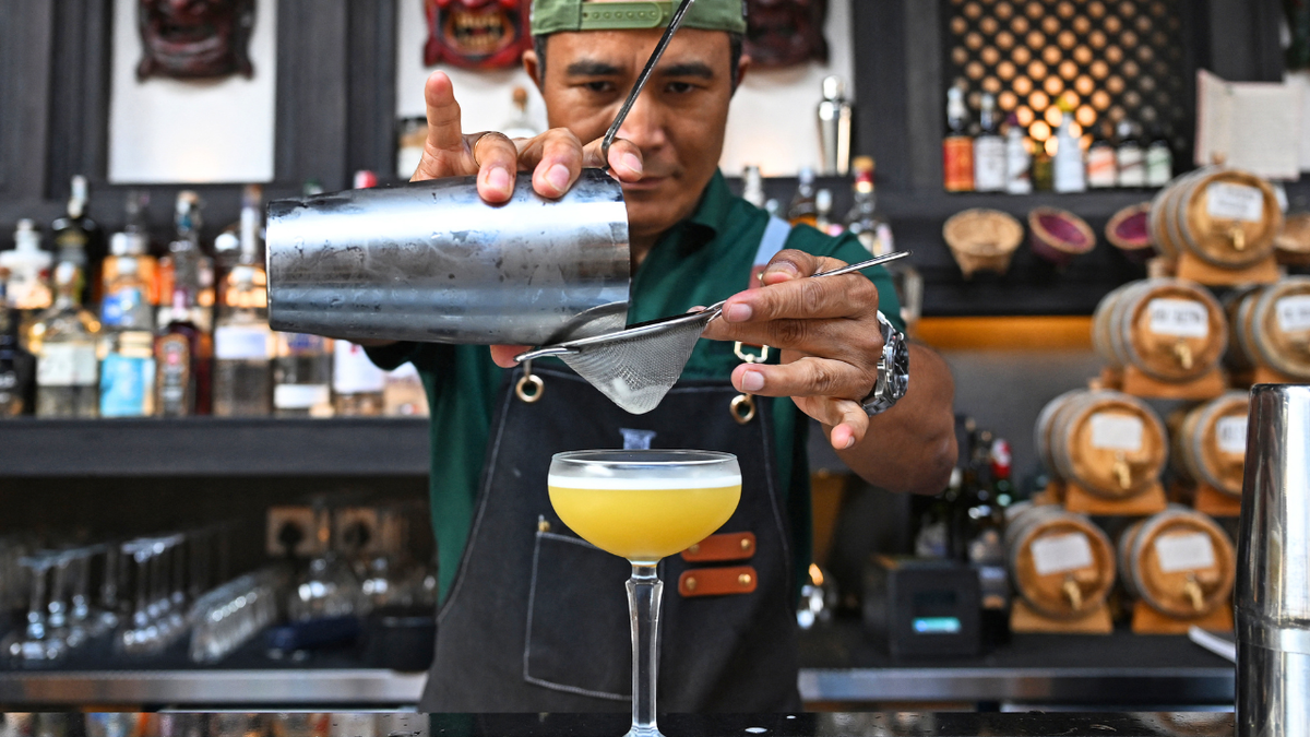 A bartender prepares a drink for a customer.
