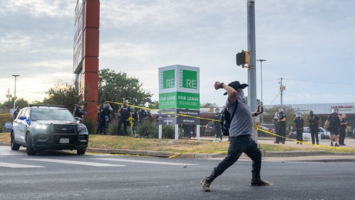 A person throws a rock at law enforcement during an ICE protest in Austin, Texas.
