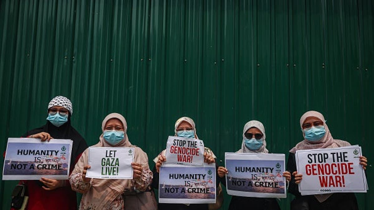Women hold placards reading 