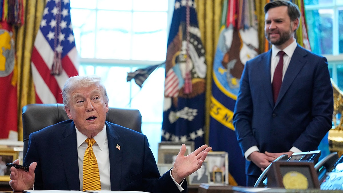 President Donald Trump speaking in the Oval Office as Vice President JD Vance listens.